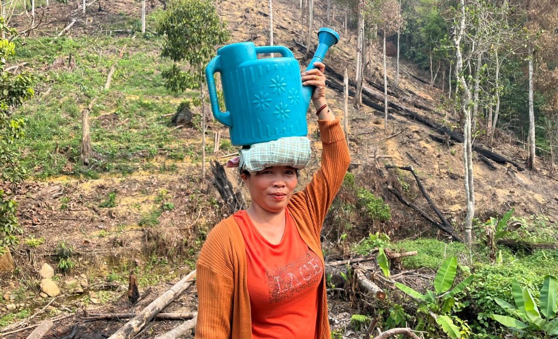 Nur Cahaya menjunjung gembor berisi air yang diambil dari sungai di lekuk bukit. Di belakangnya, lereng yang terbakar saat kemarau. (Foto: Dokumentasi Dorel Efendi)